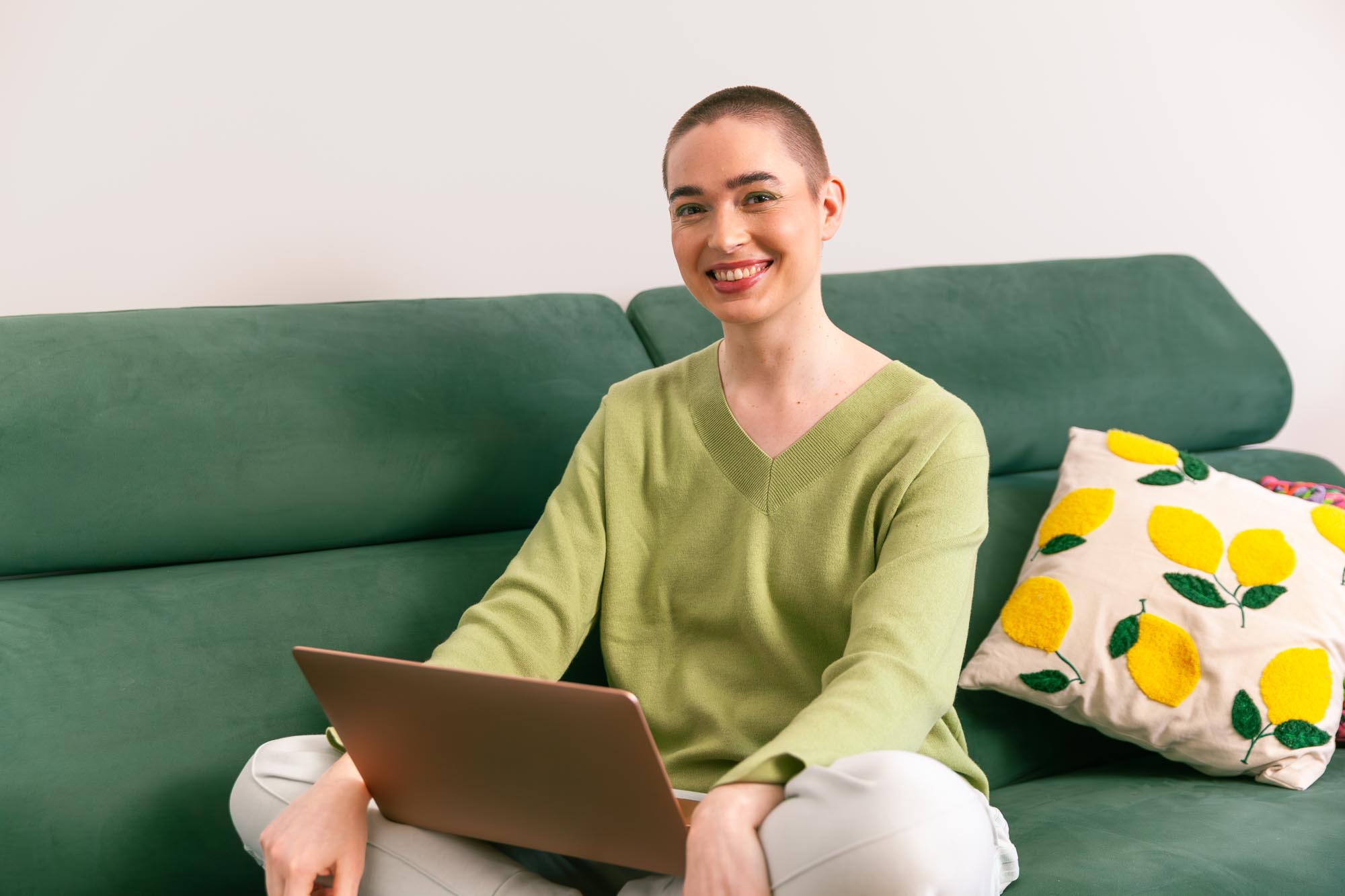 A person sitting on a sofa, working with a laptop at home