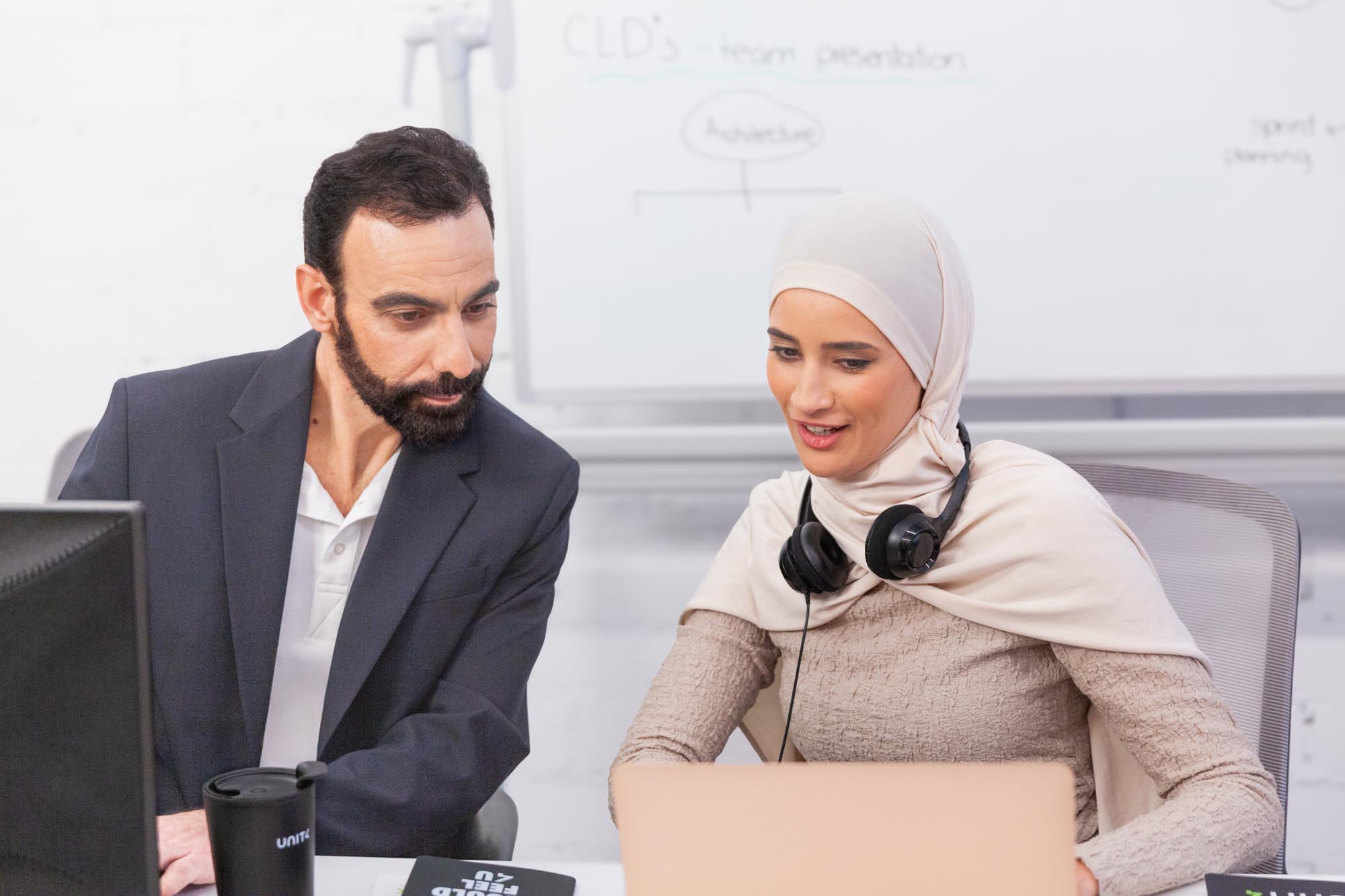 Colleagues sitting side by side, working together on computers in an office