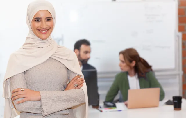 Woman smiling to the camera with colleagues working on the background