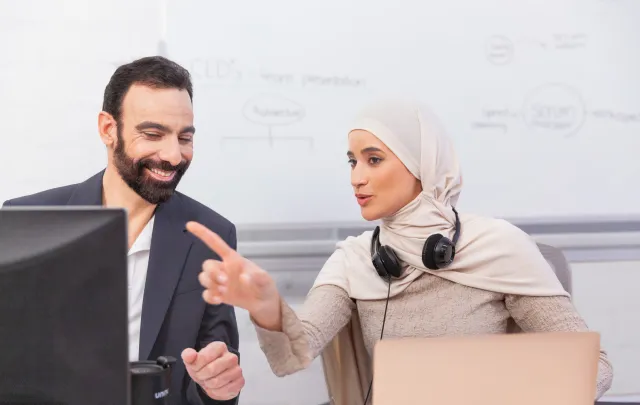  colleagues working together and sharing ideas at a computer