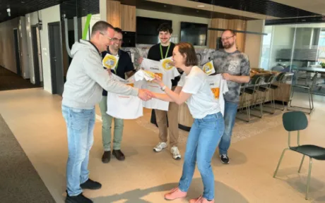 A group of five employees stand in a modern office social area during a Coding4U event.